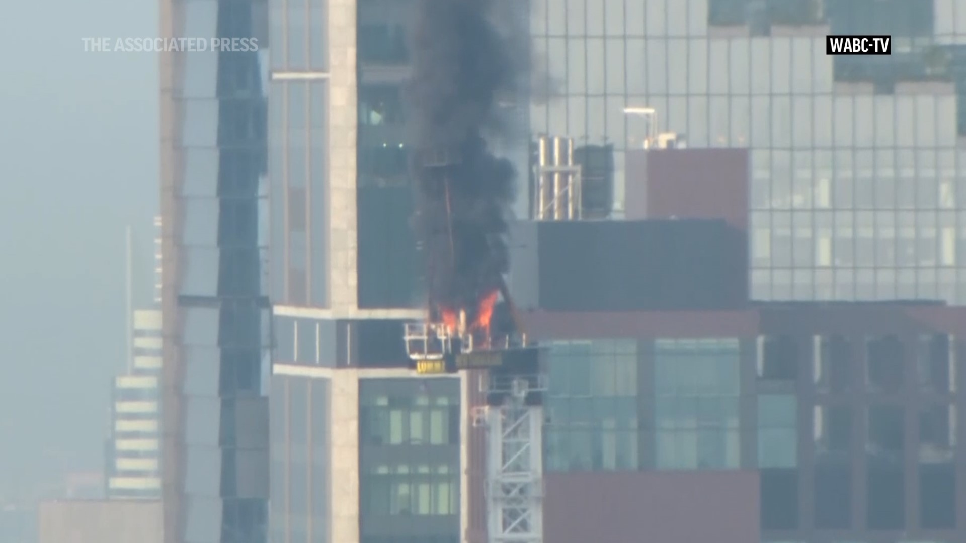 A large construction crane caught fire in Manhattan on Wednesday morning, and its arm hit a building as it crashed to the street below.