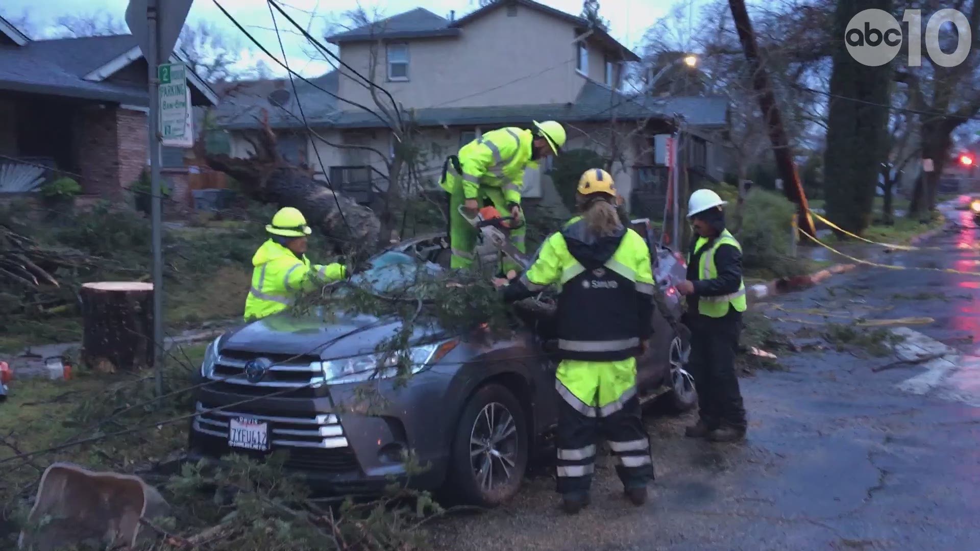 Crews work to remove a tree from the top of a car parked off 21st Street in Sacramento.