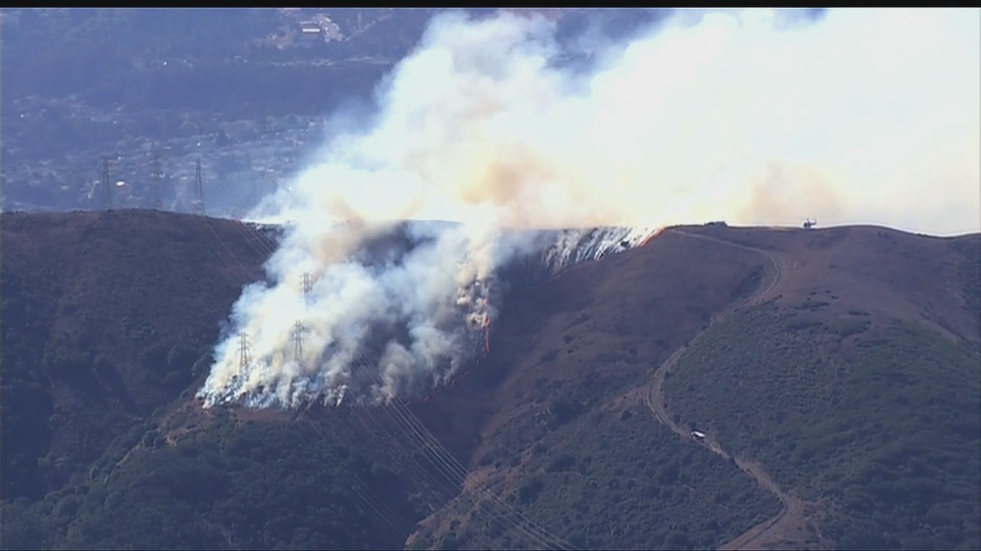 Fire crews are battling a 3-alarm brush fire on San Bruno Mountain in Brisbane, south of San Francisco. The fire is burning near a transmission line.