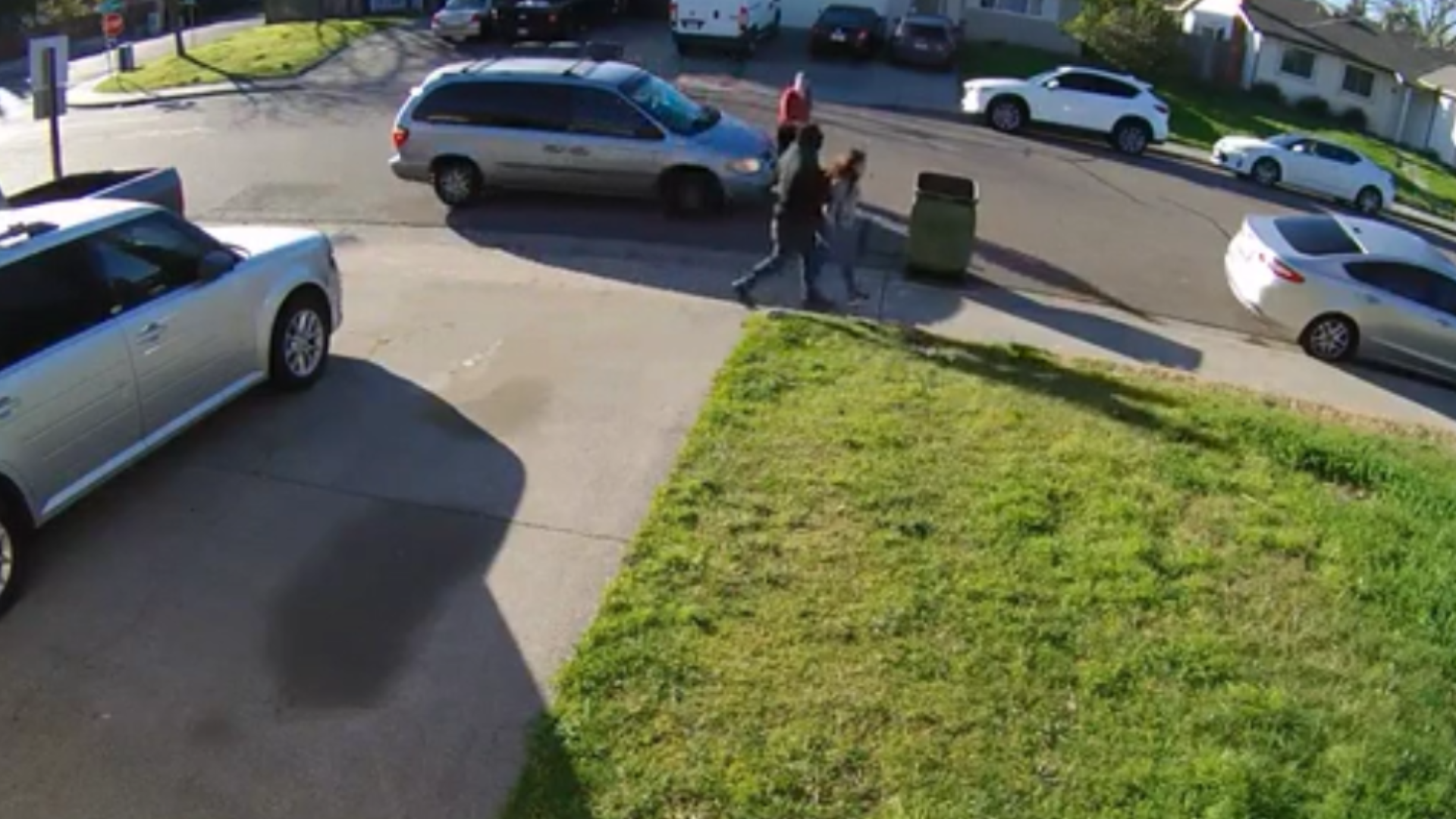 The video shows a man forcefully escorting a young girl down the sidewalk before a woman driving by in a silver minivan stops and confronts him.